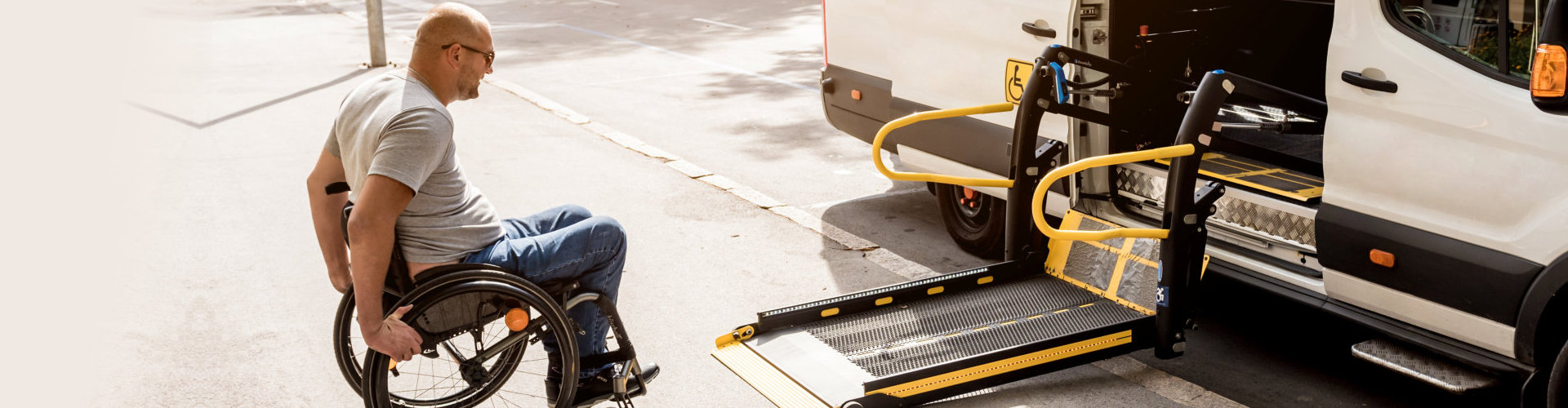 man in wheelchair getting in the car using a lifter